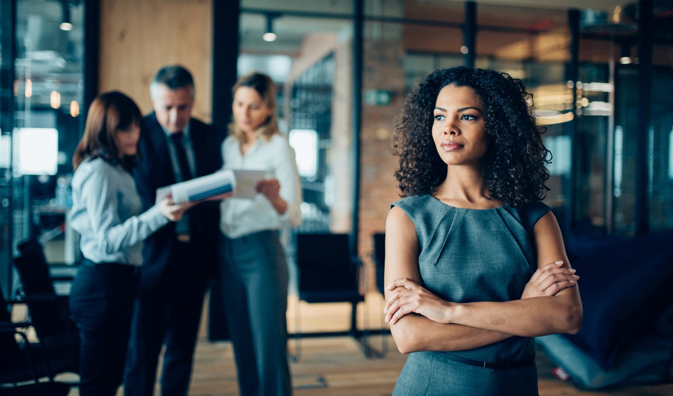 Woman with curly brown hair stands in a conference room