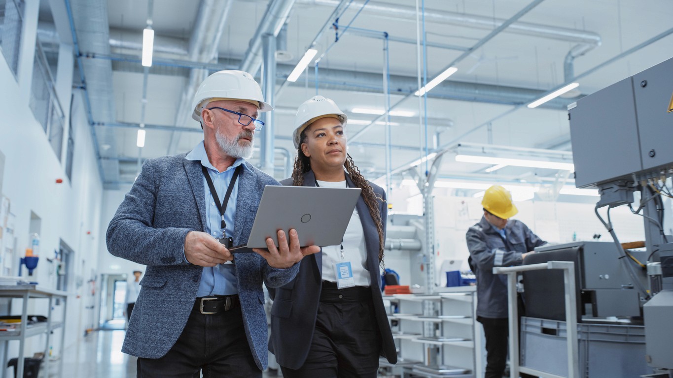 Two site managers walk the floor of a manufacturing site