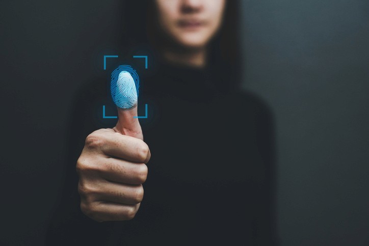 A woman presses her thumb against a fingerprint scanner