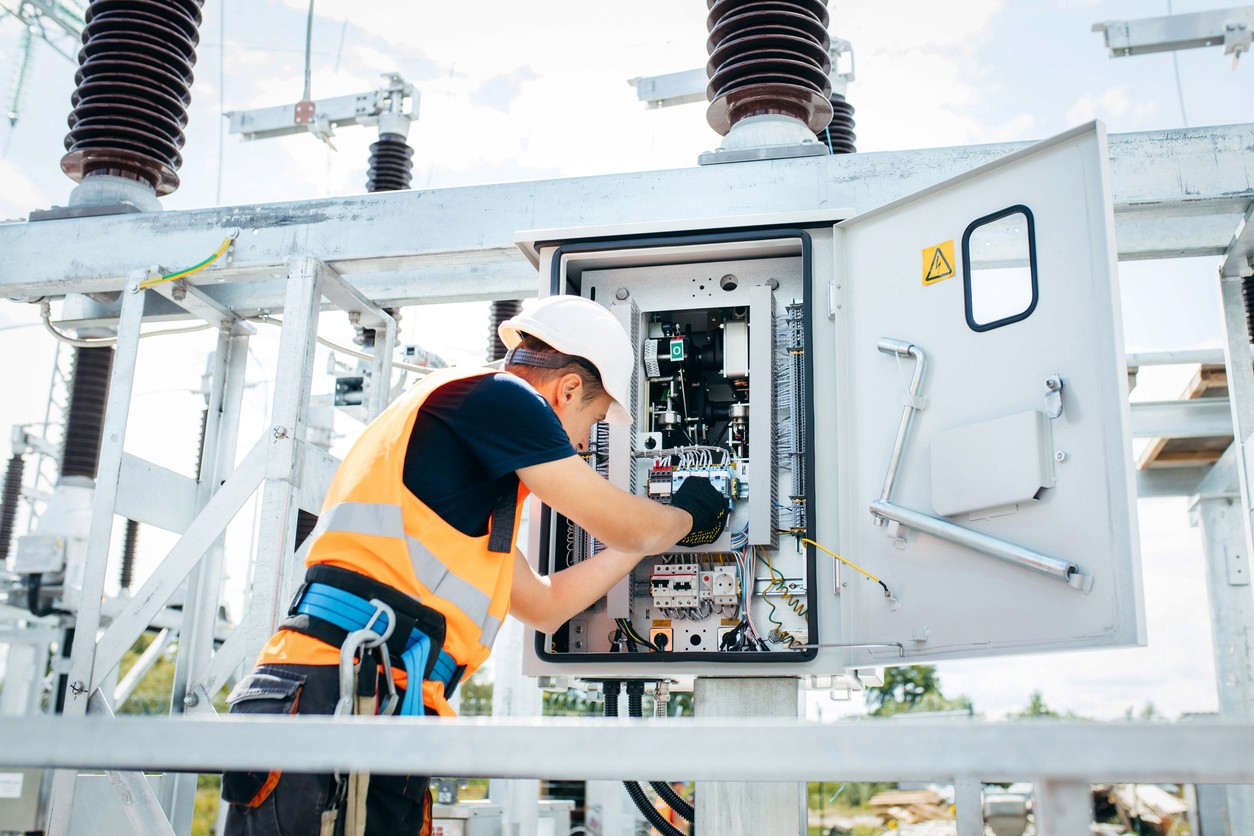 A utilities maintenance worker examines a power box at an energy facility