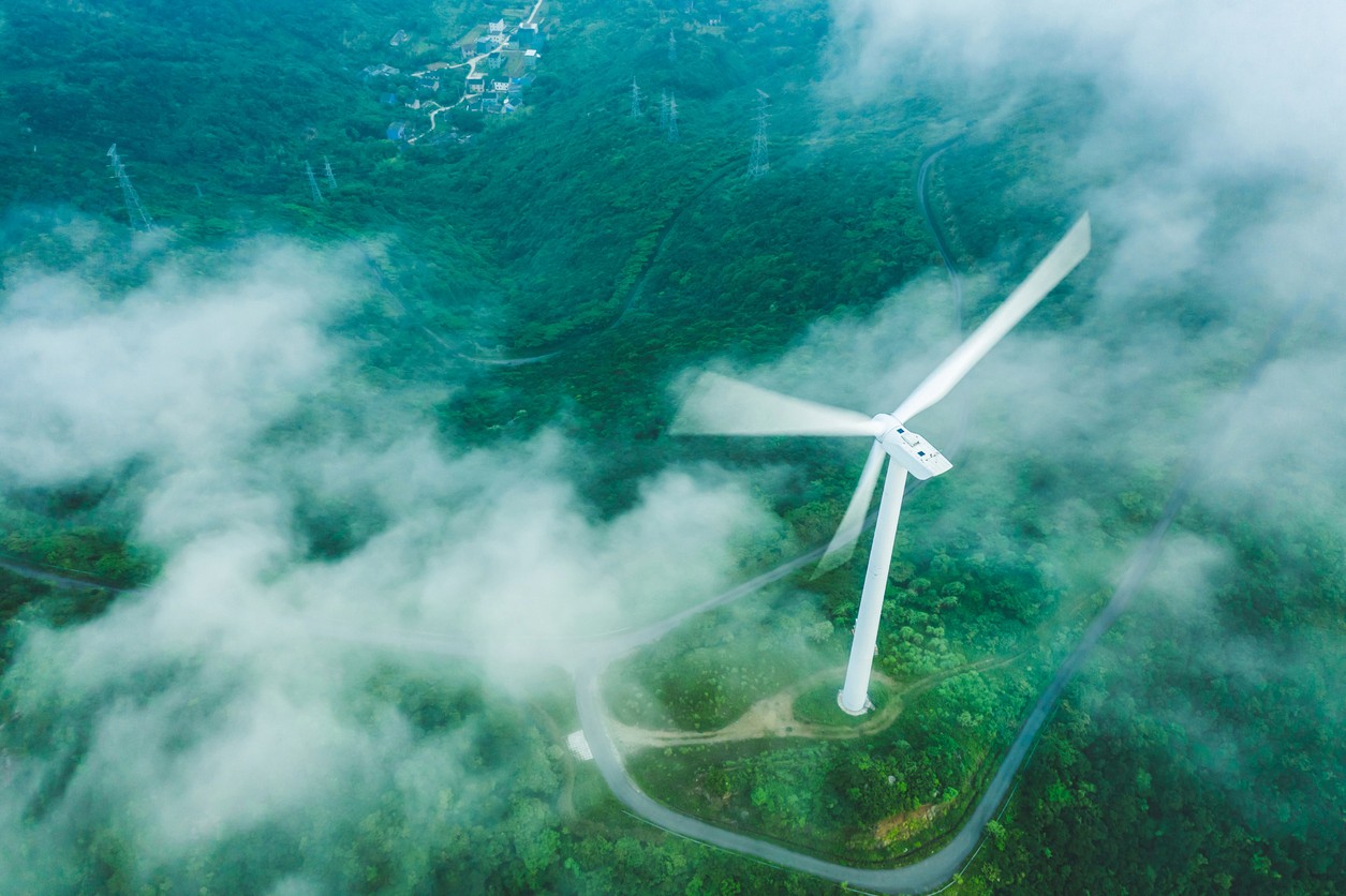 Aerial view looking down over a wind turbine with clouds in the air